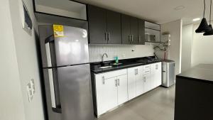 a kitchen with a stainless steel refrigerator and white cabinets at Apartamento Panoramico en Poblado, Medellin in Medellín