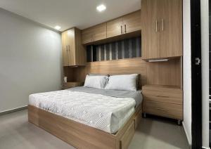 a bedroom with a large bed and wooden cabinets at Apartamento Panoramico en Poblado, Medellin in Medellín