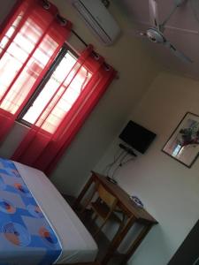 Schlafzimmer mit einem Bett, einem Schreibtisch und einem Fenster in der Unterkunft BM Akwaba in Palimé