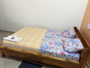 ein kleines Bett in einem Zimmer mit Blumen darauf in der Unterkunft BM Akwaba in Palimé
