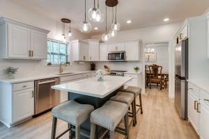 a kitchen with white cabinets and a large island with bar stools at Prime Peoria Retreat with Deck and Fireplace! in Peoria