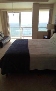 a bedroom with a large bed with a view of the ocean at Playa Bonita Rosarito in Rosarito