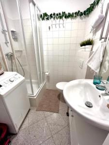uma casa de banho branca com um chuveiro e um lavatório. em Magic Vienna Balcony Apartment em Viena