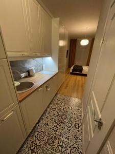 a kitchen with white cabinets and a sink and a floor at Jūros apartamentai in Klaipėda