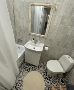 a bathroom with a sink and a toilet and a mirror at Jūros apartamentai in Klaipėda