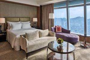 a hotel room with a bed and a couch and a table at The Ritz-Carlton Hong Kong in Hong Kong