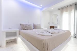 a white bedroom with a bed and a mirror at Studios Farma in Agia Anna Naxos