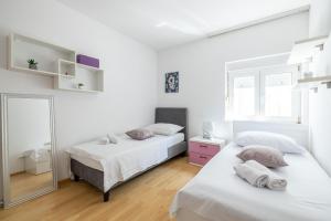 Habitación blanca con 2 camas y espejo. en Apartments with a parking space Solin, Split - 21445, en Solin