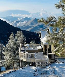 a house covered in snow with mountains in the background at Beautiful View Point Villa in Conifer