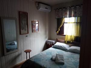 um pequeno quarto com uma cama e uma janela em Casa da vovó em Gramado