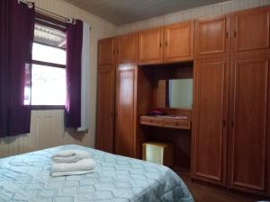 um quarto com uma cama, armários de madeira e uma janela em Casa da vovó em Gramado
