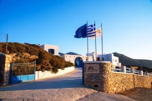 a flag flying in front of a building with a gate at Amorgion Village in Katapola