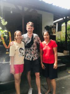 un hombre y dos mujeres parados frente a una casa en Yasa Backpackers house en Ubud