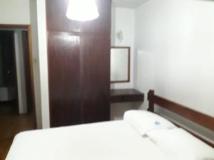 een slaapkamer met een bed en een houten kast bij Chalés Holiday House in Rio Quente
