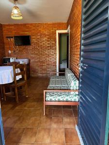 Chalés Holiday House في ريو كوينتي: غرفة مع مقعد وجدار من الطوب