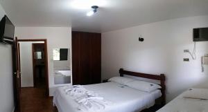 a bedroom with two beds with white sheets and a mirror at Chalés Holiday House in Rio Quente +11 photos