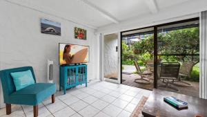 sala de estar con TV y silla azul en Casa de Emdeko 121 en Kailua-Kona