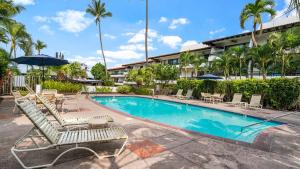 una piscina con tumbonas y sombrilla en Casa de Emdeko 121, en Kailua-Kona