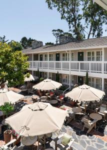 a hotel with tables and umbrellas in front of it at Le Petit Pali at 8th Ave in Carmel