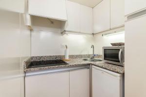 a white kitchen with a sink and a microwave at Comodidad y elegancia a lado de la Diagonal in Barcelona