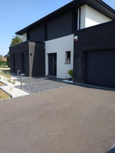 um edifício preto e branco com duas portas de garagem em Havre de modernité à la campagne proche Arras em Dainville