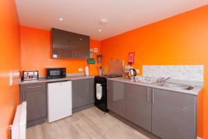 uma cozinha com armários cinzentos e paredes laranja em Colourful Mongolian Yurt enjoy a new experience em Turriff