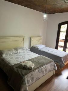 two beds in a bedroom with two stuffed animals on the bed at Pousada Recanto Aurora in Petrópolis