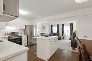 a kitchen with white appliances and a living room at Konia Suites in Orangeville