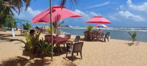 una playa con mesas, sillas y sombrillas en la playa en Sandul Villa, en Beruwala