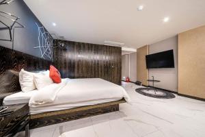una camera con un grande letto e una TV a schermo piatto di Hotel Ritz a Suwon