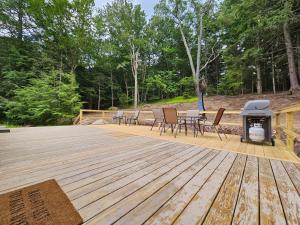 a wooden deck with a grill and tables and chairs at Tranquil renovated house in woods - great for families year around in Tannersville