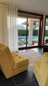 ein Wohnzimmer mit einem Sofa und Poolblick in der Unterkunft Villa Deluxe - Quinta do Outeirinho in Celorico de Basto