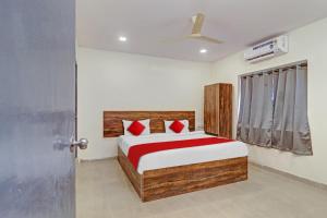 1 dormitorio con 1 cama con almohadas rojas y puerta en OYO Flagship 81135 Hotel R Square Inn en Hyderabad
