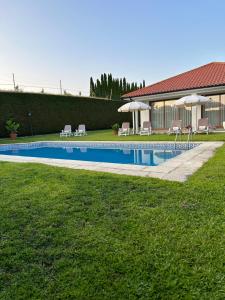 a swimming pool with chairs and umbrellas next to a house at Villa Deluxe - Quinta do Outeirinho in Celorico de Basto