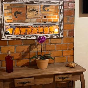 a painting of a brick wall with a table with a flower at Hotel Pousada Praia do Farol in Ilha do Mel