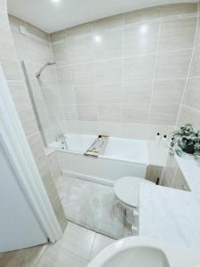 uma casa de banho com uma banheira, um WC e um lavatório. em Prime London Living 2-Bedroom Beauty! em Londres