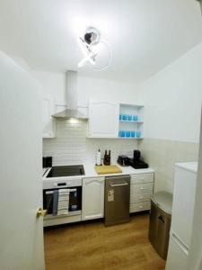 a white kitchen with a stove and a ceiling fan at Prime London Living 2-Bedroom Beauty! in London