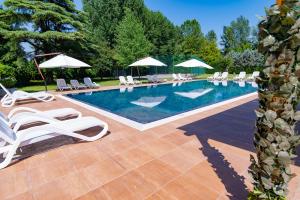 una piscina con tumbonas y sombrillas blancas en Villa Vitti's - Verona est en San Martino Buon Albergo