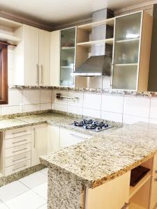a kitchen with white cabinets and granite counter tops at Moradia Compartilhada Pelotas in Pelotas