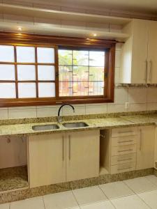 a kitchen with two sinks and a window at Moradia Compartilhada Pelotas in Pelotas