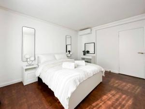 um quarto branco com uma cama branca e 2 candeeiros em London's Charm Modern 2BR Marylebone's Best Spot em Londres
