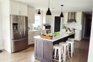 una cocina con nevera de acero inoxidable y armarios blancos en Coco home en Charlottetown