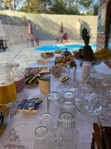 uma mesa com copos e comida e uma piscina em Pousada por do soll em Serra do Cipó