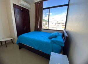een slaapkamer met een blauw bed en een raam bij Departamento amoblado con piscina en San Clemente in San Clemente