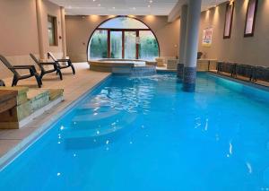 a large swimming pool with blue water in a building at Le Rioumajou 2 - Grand T4 - Piscine - Centre St Lary in Saint-Lary-Soulan