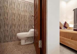 a bathroom with a toilet and a bed at Ditha Guest House in Ubud