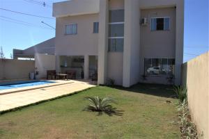 una gran casa blanca con un patio delante en Sobrado espaçoso com piscina com ar na suite, en Chapada dos Guimarães