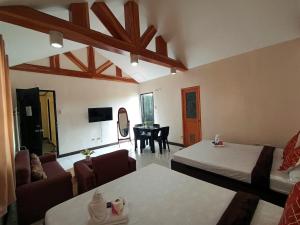 a room with two beds and a living room with a table at La Gracia Apartelle in Tagaytay