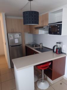 a kitchen with a white counter and a red stool at Departamento Peñuelas Sol Marina III La Serena - Coquimbo in Coquimbo