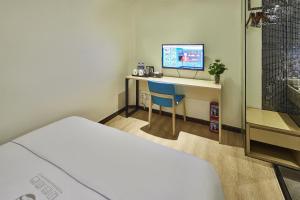 a room with a bed and a desk with a television at Insail Hotels Guangzhou XiMenKou Subway Station Branch in Guangzhou